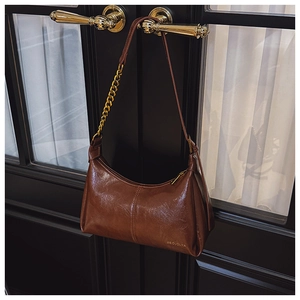 Detail of brown hobo bag with gold chain strap and embossed logo on oil wax leather