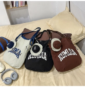 Detailed shot of three nylon drawstring tote bags with cute mini hat charms on a bed