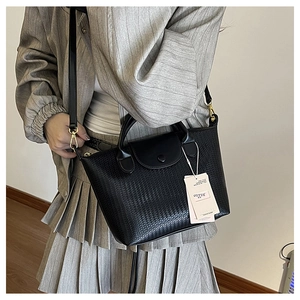 Dettaglio della trama intrecciata nera e fibbia dorata su una borsa a tracolla elegante