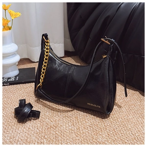 Detail of black hobo bag with bold gold chain and adjustable shoulder strap on side