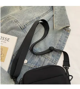 Dettaglio della tracolla regolabile e degli accessori neri sulla borsa a tracolla nera