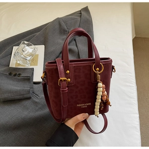 Detail of burgundy leopard embossed bucket bag with gold hardware and beaded charm