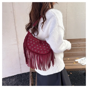 Detail van bordeauxrode suède tas met franjes en metalen ogen in boho-stijl