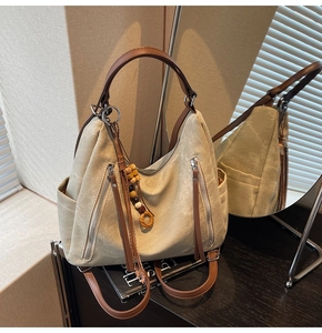 Detail of beige hobo bag featuring ethnic beads and a decorative zipper pocket