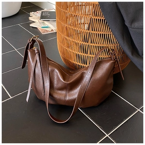 Detail of dark brown leather texture with adjustable strap and gold metal buckle on the bag