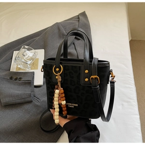 Detail of leopard embossed texture on black bucket bag with a colorful beaded pendant