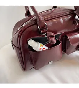Detail of burgundy glossy leather handbag featuring functional external side flap pockets
