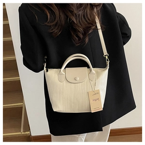 Dettaglio della trama intrecciata beige e della pelle liscia della borsa a tracolla