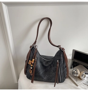 Detail of grey washed leather hobo bag with side zippers and decorative beads