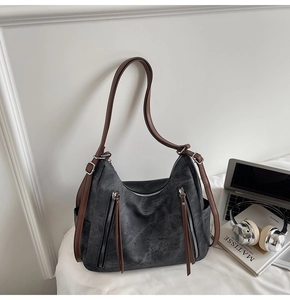 Close-up of deep grey tote bag with brown straps and dual decorative zippers
