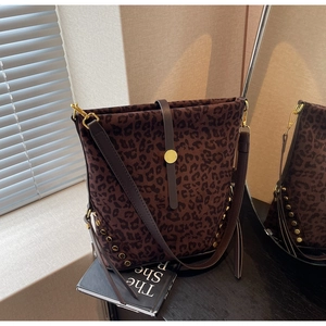 Detail of leopard print bucket bag featuring gold rivets and elegant leather straps