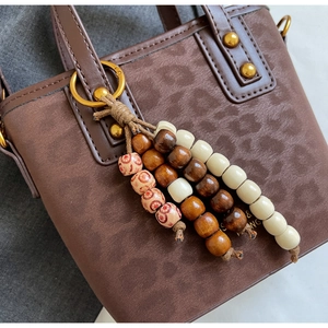 Close-up of leopard pattern embossing and beaded tassel charm on brown handbag