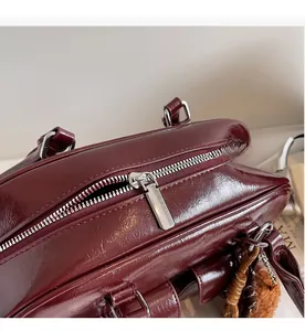 Close-up of smooth silver metal zipper on vintage burgundy leather bowling bag detail
