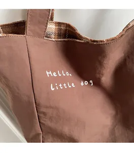 Detail of a brown canvas bag with plaid lining and Hello Little Dog graphic print