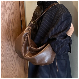 Detail view of a large brown hobo bag with fringe zipper and smooth faux leather texture