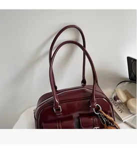 Detail of burgundy glossy leather handbag with functional pockets and thin shoulder straps