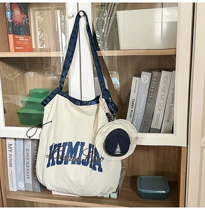 Detail of a large nylon tote bag in cream with blue straps and matching mini coin purse