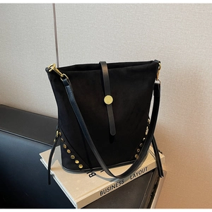 Detail of black suede bucket bag with gold studs and round metallic clasp closure