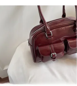 Detail of dark red glossy leather boston bag with silver buckles and large capacity