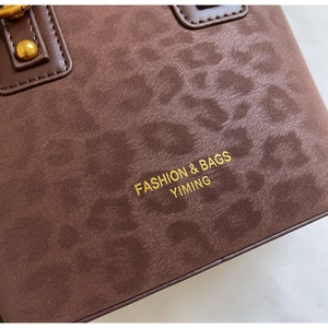 Detail of leopard print suede handbag with gold rivets and brand logo texture