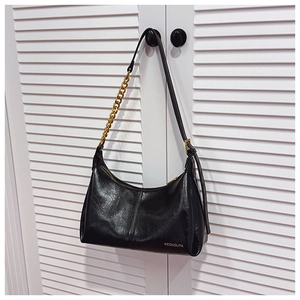 Close-up of black moon bag with glossy leather texture and golden chunky chain handle