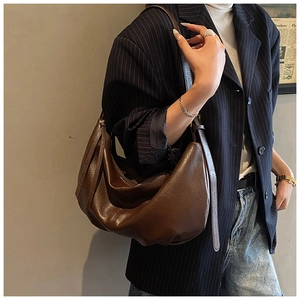 Detail of adjustable strap and crescent shape on dark brown leather shoulder bag