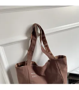 Detail of comfortable shoulder straps and checkered lining on canvas tote bag