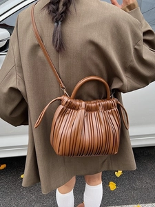 Brown ruched handbag with adjustable crossbody strap in a pleated faux leather finish
