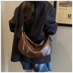 Detail of dark brown leather crossbody bag with pleated texture and vintage moon silhouette
