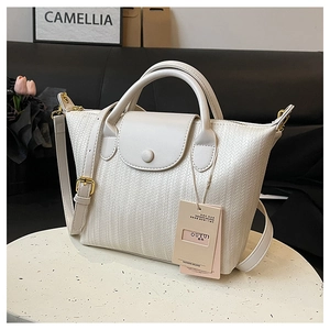 Dettaglio della borsa a mano color crema con trama intrecciata, patta e zip metallica