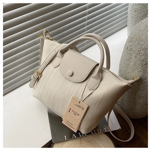Dettaglio della borsa a tracolla beige a trama intrecciata con manici e cinturino