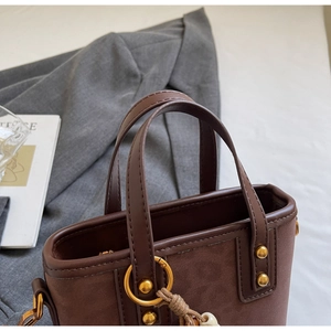 Close-up of leopard print handbag with golden metal ring and woven charm detail