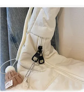 Detail of white quilted cloud bag featuring dual metal zippers and lovely hat charm