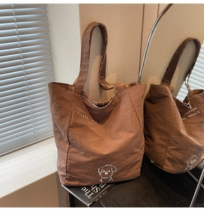 Detail view of brown tote bag with white cartoon dog print and retro plaid lining