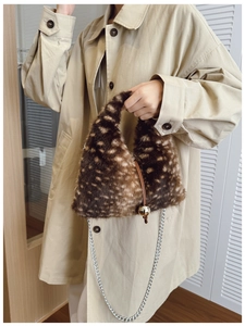 Détail d'un sac à main triangulaire en fausse fourrure motif cerf avec breloque dorée