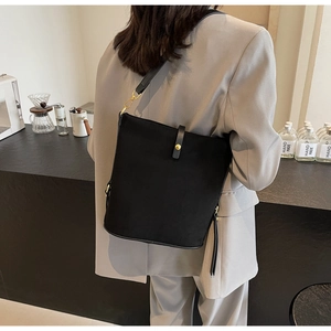 Detail of minimalist black bucket bag featuring golden clasp and sleek leather strap décor