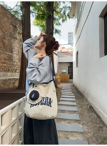 Detail of cream canvas tote bag with navy straps and matching zip pouch attachment