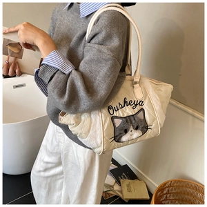 Dettaglio della borsa tote beige trapuntata con bordo in peluche e ricamo a gatto