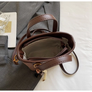 Detail shot of the dark brown bucket bag's interior zipper pocket and gold hardware