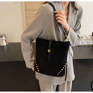 Detail shot of black suede bucket bag with gold studs and decorative metal ring