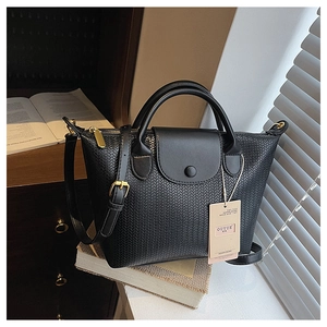 Dettaglio della borsa nera intrecciata con cerniera dorata e patta in pelle elegante