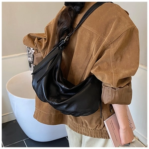 Model wearing a large black pleated crescent shoulder bag with adjustable strap