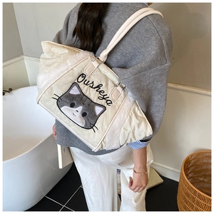 Dettaglio della borsa tote trapuntata con ricamo a gatto e bordo in peluche sulla tracolla