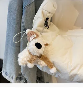 Close-up of a plush dog bag charm with a brown knit hat and scarf on a canvas bag