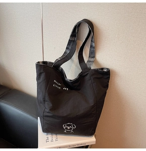 Detail of the large black tote bag with cute dog print and stylish checkered lining