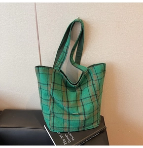 Detail of green plaid canvas tote bag with metal bar trim and large capacity design