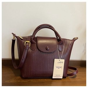 Dettaglio di borsa bordeaux con trama intrecciata e finiture in metallo dorato