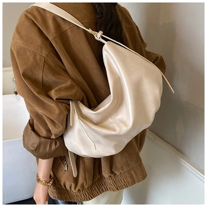 Detail of soft cream leather hobo bag with gold buckle and pleated texture on the strap