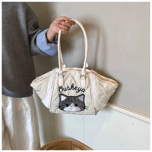 Dettaglio della borsa tote trapuntata crema con ricamo a gatto e pannelli in peluche