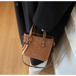 Leopard print bucket bag with gold studs and ethnic bead charm on leather strap